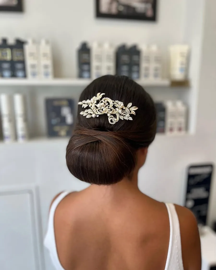 A sleek low bridal chignon finished with a jewelled hair comb