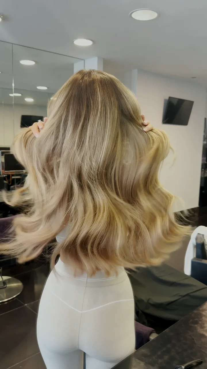 Long blended blonde extensions being curled after a weft refit