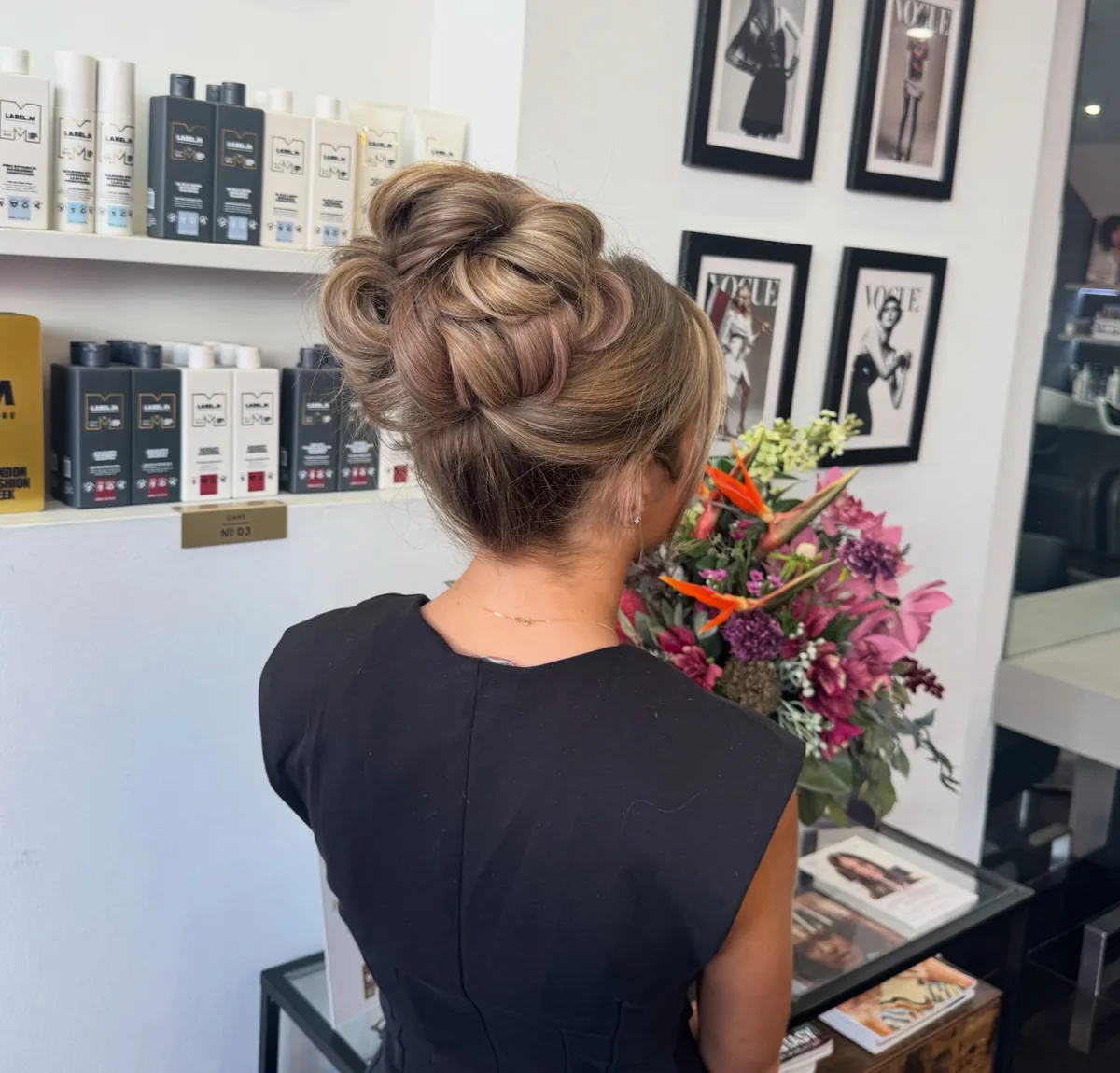 A voluminous textured high bun in soft brown with blonde tones